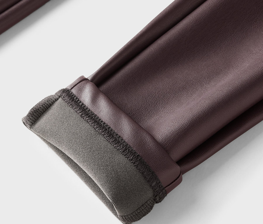 Egy barna bőr nadrág részlete, felhajtott szegéllyel és szürke béléssel.