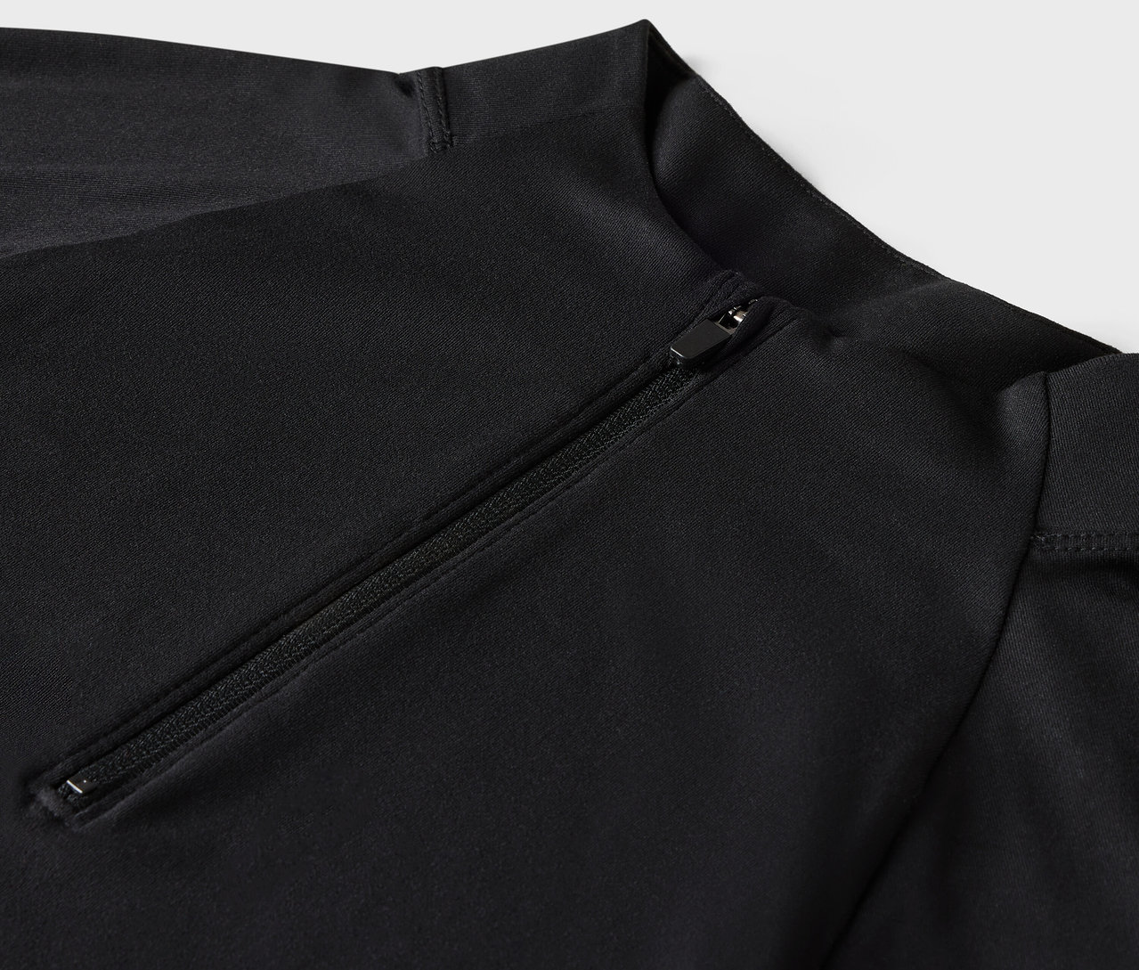 Egy fekete, hosszú ujjú fürdőruha részlete cipzárral.