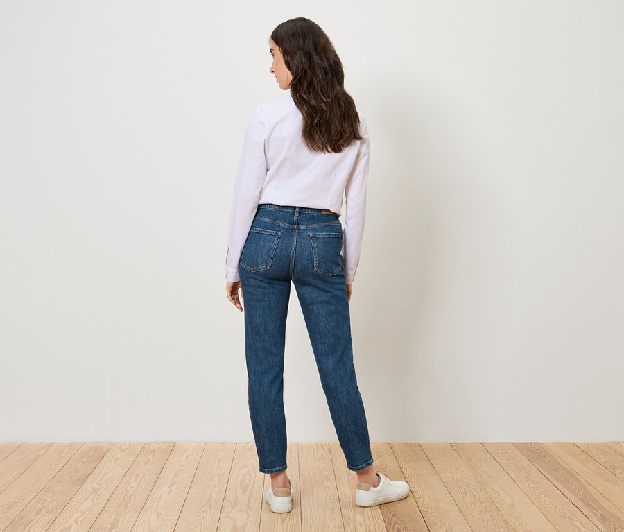 Egy nő háttal áll a kamerának, és egy Mom Jeans – Fit »Nyla«, középkék színű farmert visel.