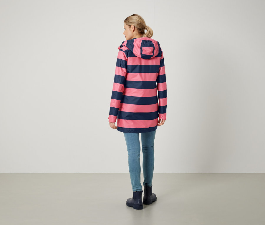Hátulról egy nő rózsaszín-kék csíkos kabátot, farmert és gumicsizmát visel.