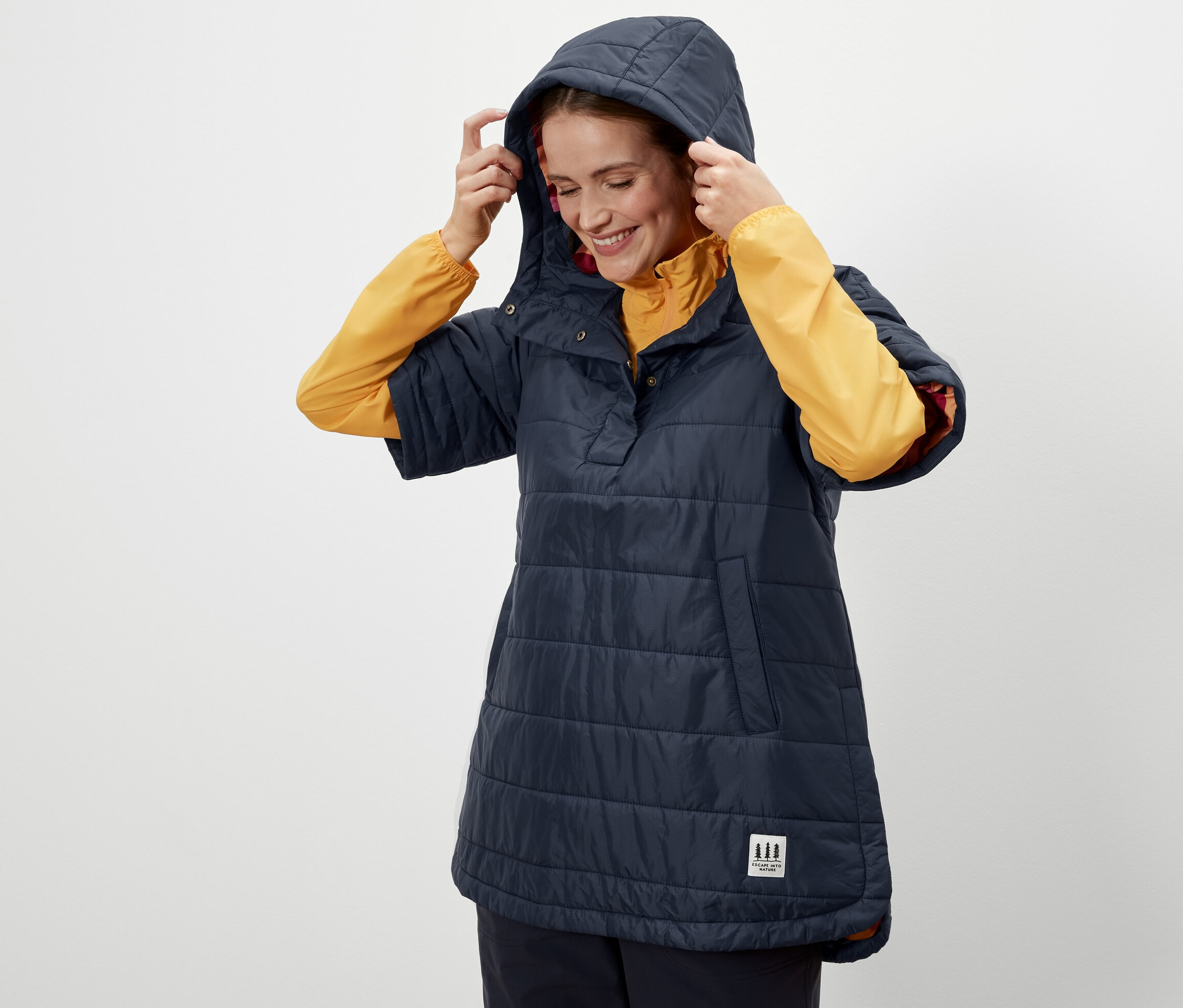 Nő igazítja a kapucnit a sötétkék női túraponcsón.