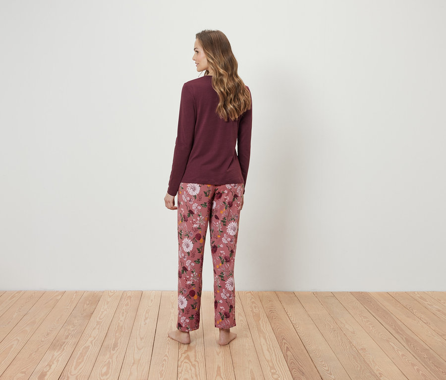 Hátulról látható nő bordó hosszú ujjú felsőben és rózsaszín virágos pizsamanadrágban.
