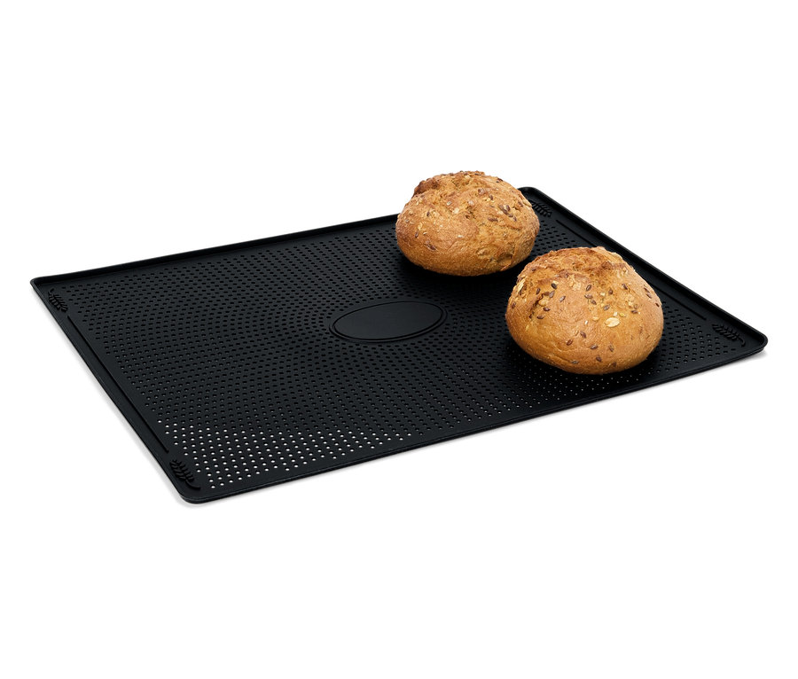 Két zsemle fekszik egy fekete, perforált sütőlapon.