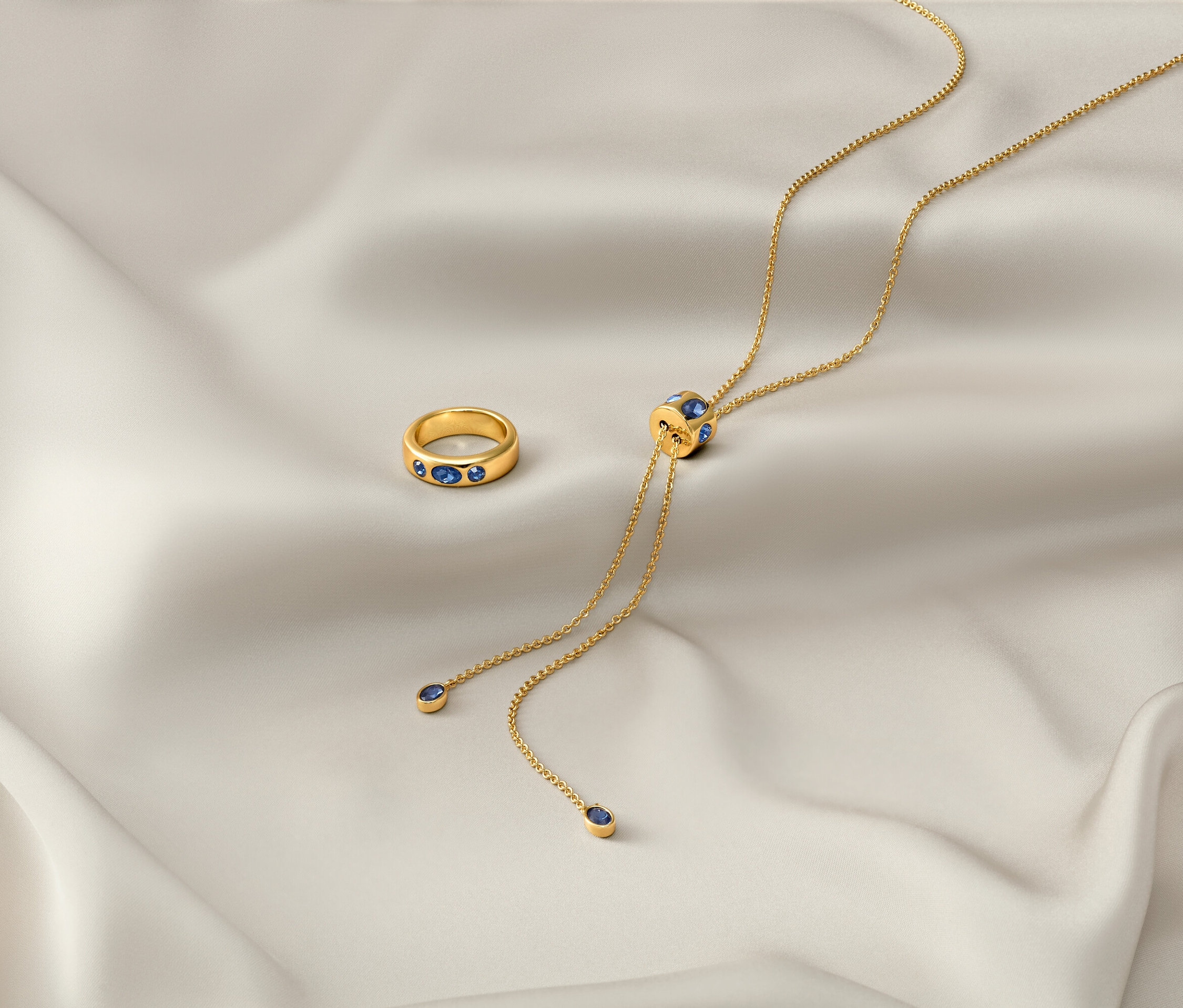 Egy fehér kendőn egy arany »Iconic« nyaklánc és egy arany »Iconic« gyűrű fekszik.