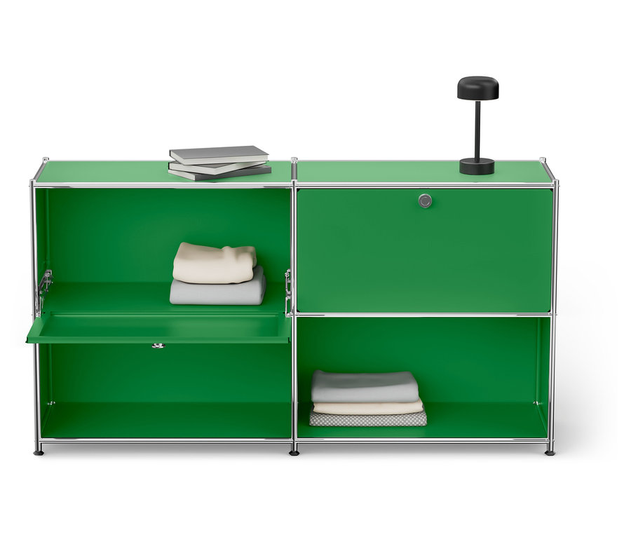 Zöld szekrény ezüst kerettel, két polccal, könyvekkel, lámpával és összehajtogatott ruhákkal.