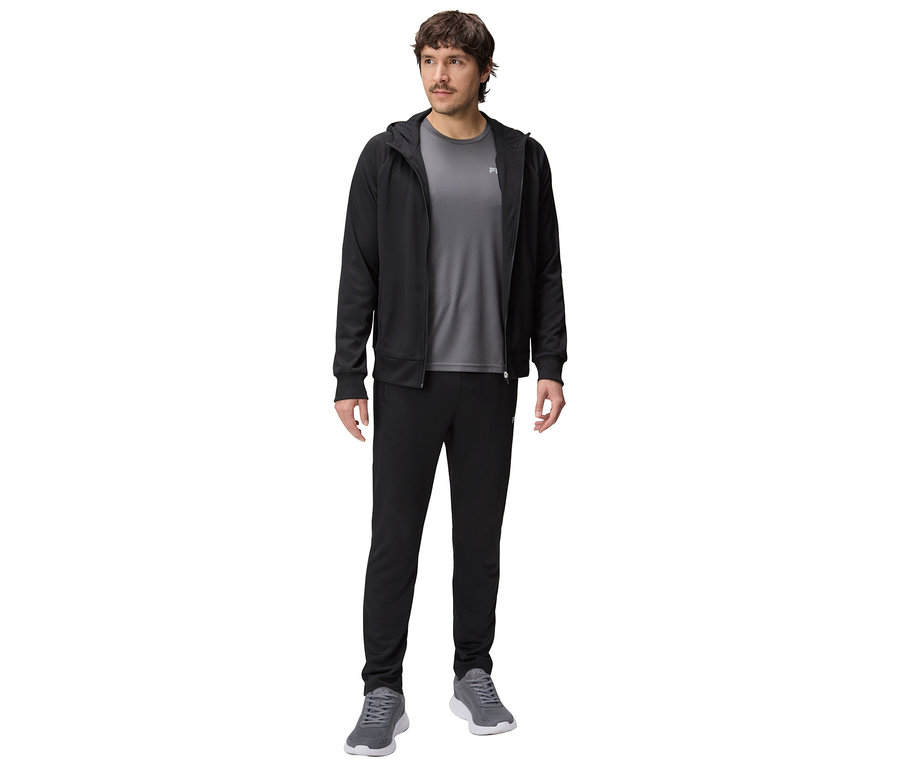 Férfi fekete kapucnis tréningdzsekiben, szürke pólóban és fekete tréningnadrágban, szürke tornacipővel.