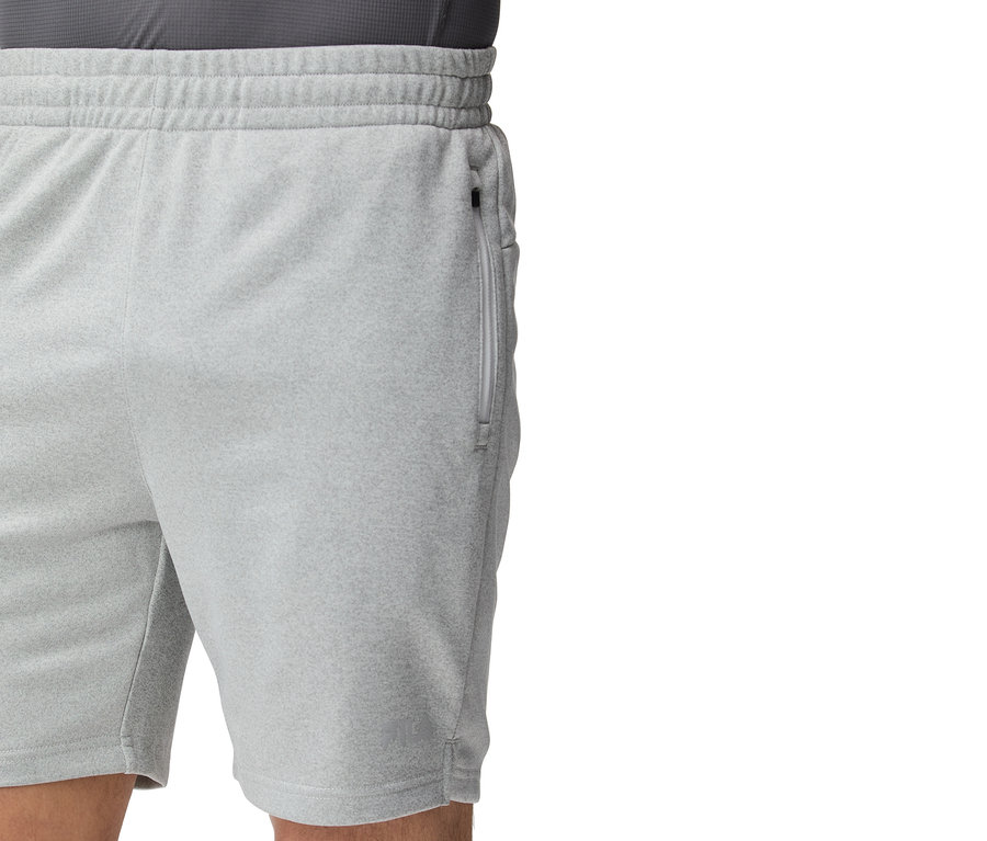 Közelkép egy világosszürke edzősortról, zsebén cipzárral.