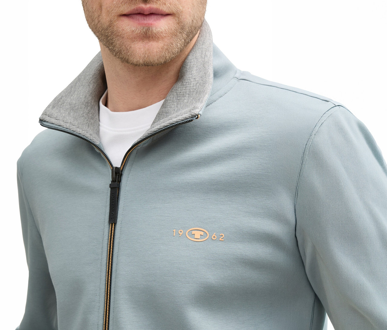 Közeli kép egy férfiról, aki Tom Tailor állógalléros szürkés menta szabadidőfelsőt visel, cipzárral, szürke gallérral.