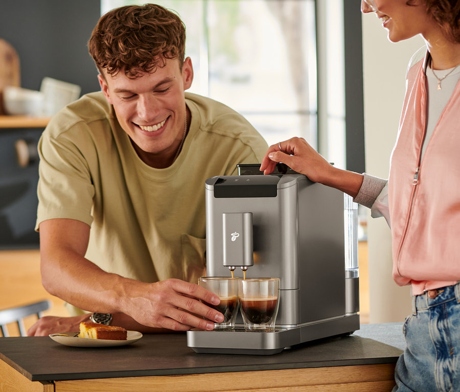 Egy férfi nézi, ahogy a kávé a Titanium Silver színű »Esperto2 Caffè« automata kávéfőzőből két pohárba folyik.
