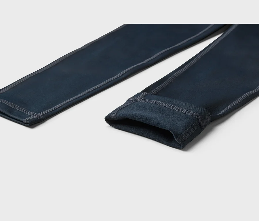 Sötétkék leggings szürke varrással és puha, bolyhos belső béléssel, világos háttéren fekve.