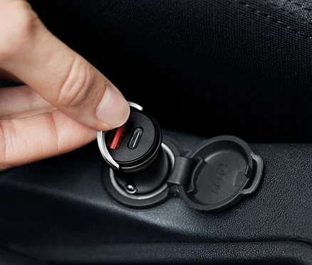Kéz csatlakoztat egy fekete USB-C autós töltőt.