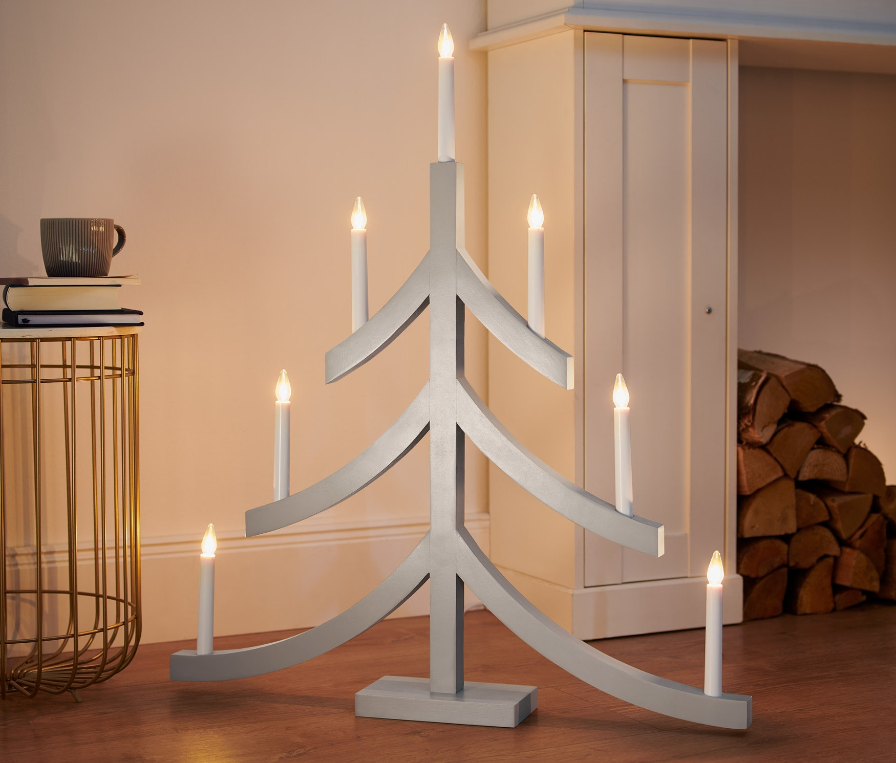Egy szürke, karácsonyfa alakú XL-es LED-es gyertyatartó áll a padlón.