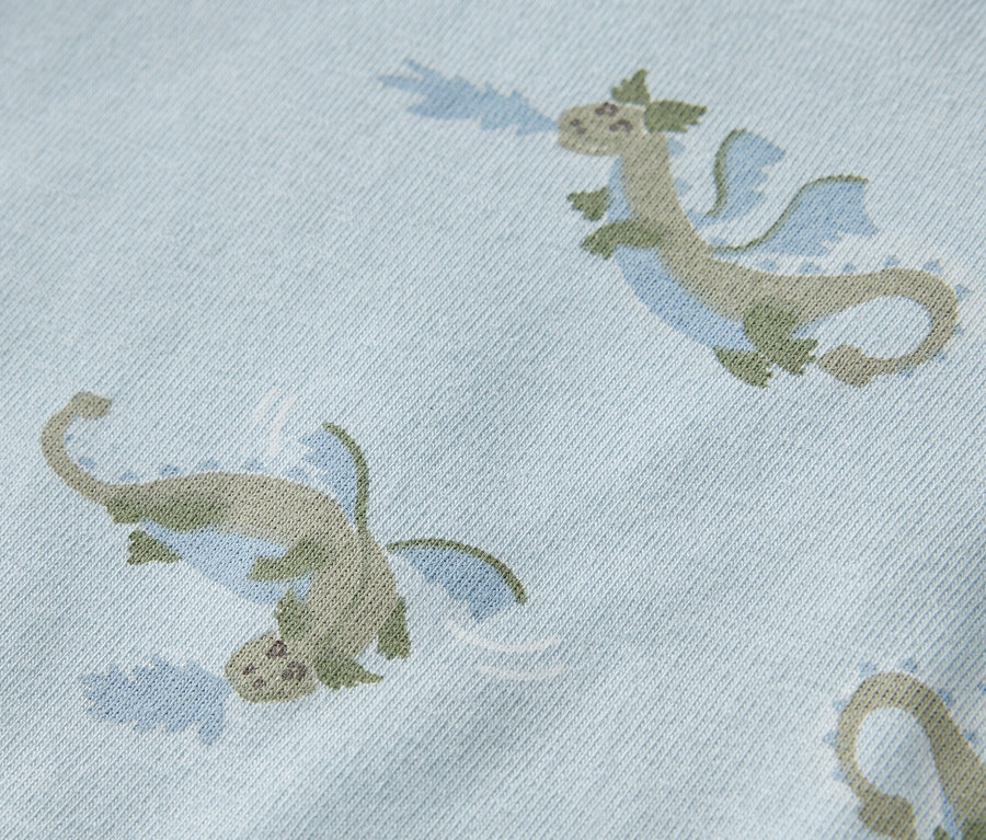 Egy világoskék body közelképe zöld sárkányokkal.