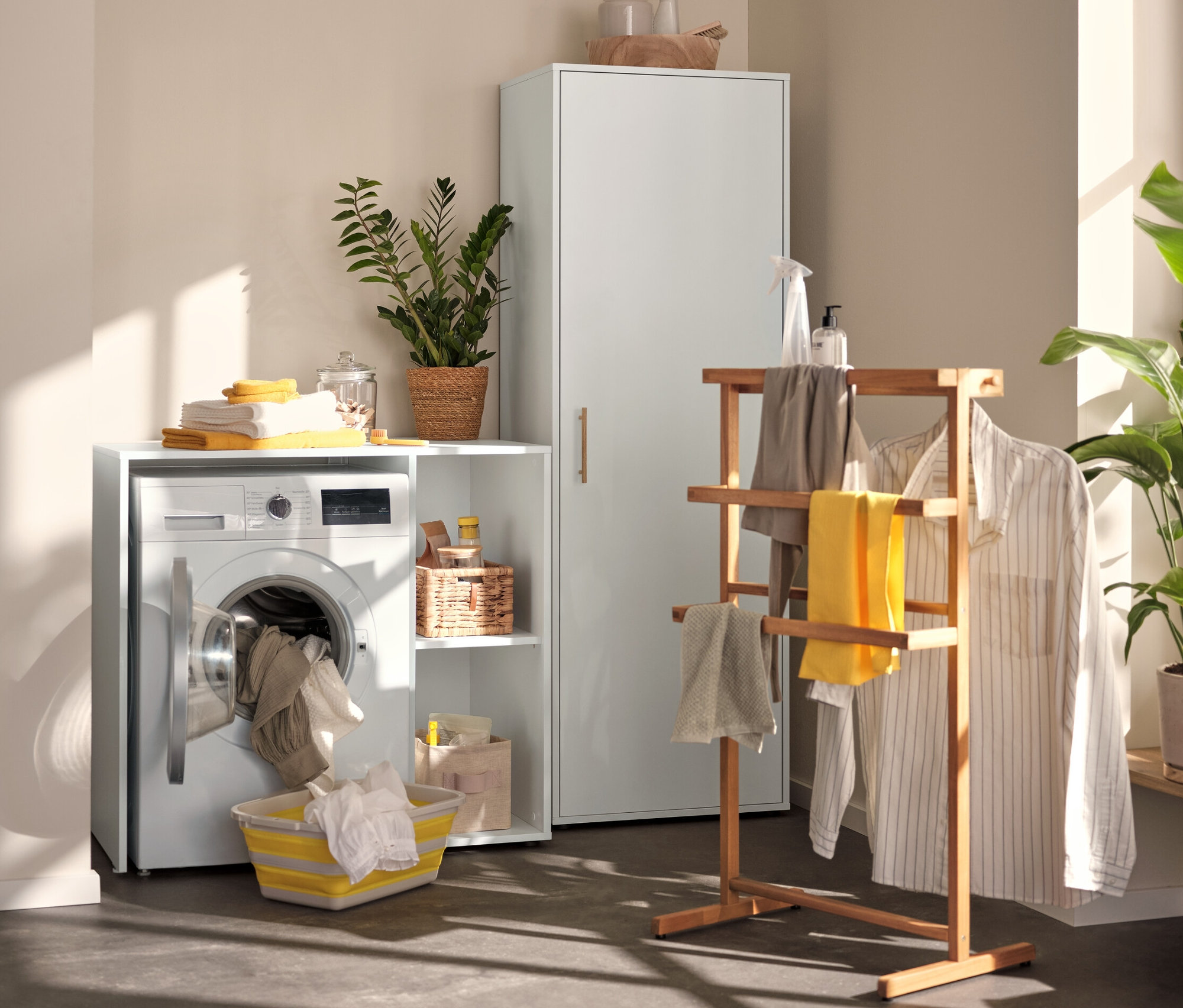 A mosókonyhában egy szekrény háztartási eszközökhöz, egy mosógép szekrény és egy szobainas látható.