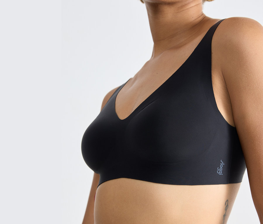 Egy nő törzse, aki fekete sloggi ZERO Feel 2.0 puha melltartót visel.