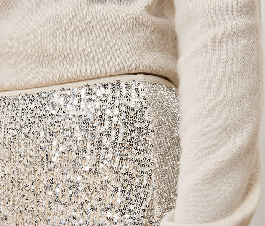 Női szett részlete: krémszínű pulóver és ezüst flitteres szoknya.