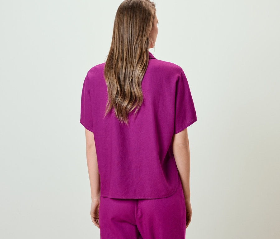 Hátulról látható egy nő egy fukszia lenvászon női rövid ujjú ingblúzban.