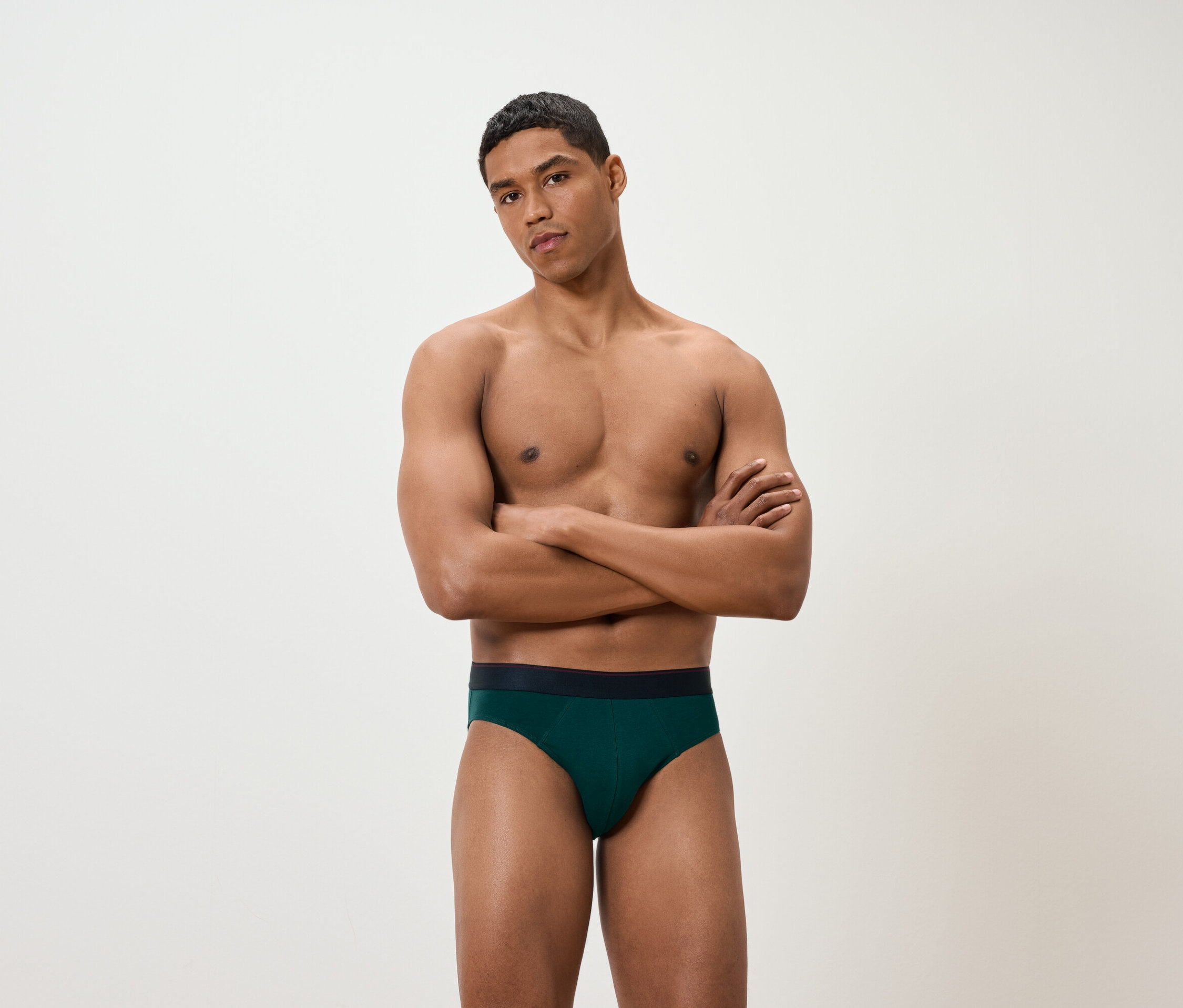 Egy férfi keresztbe tett karokkal zöld alsónadrágot visel.