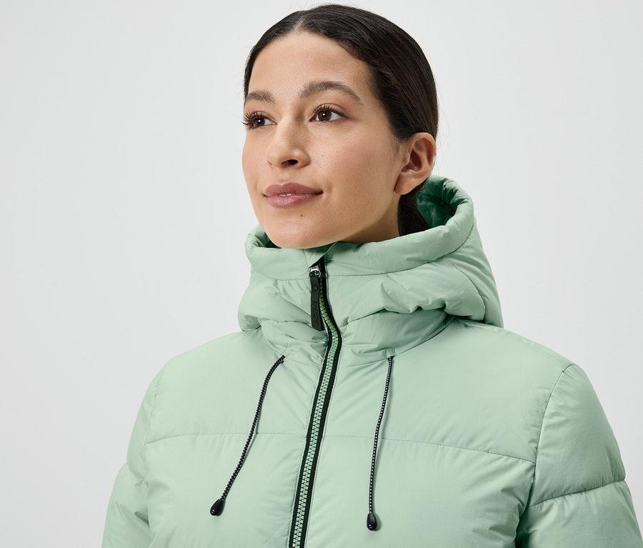 Nő visel egy világoszöld színű pehelykabátot.