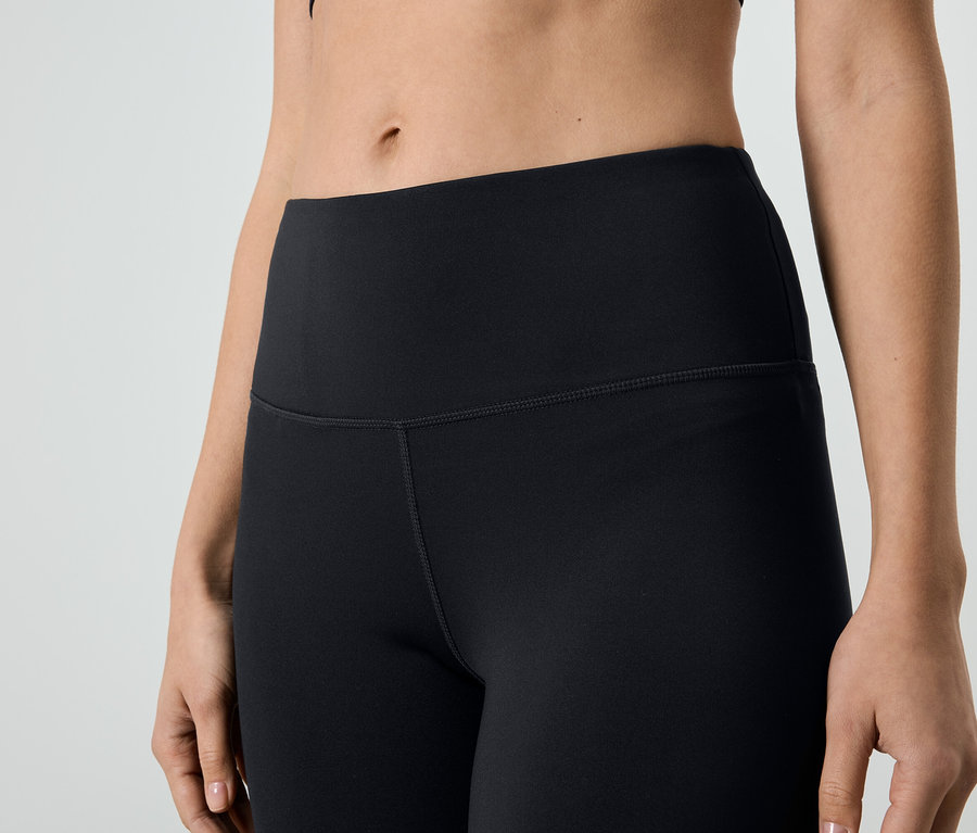 Egy fekete leggingset és sportfelsőt viselő nő közeli felvétele.