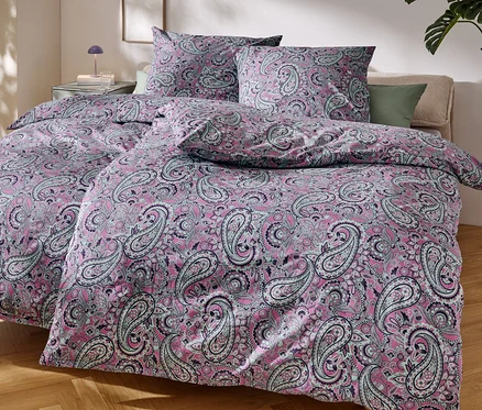 Egy ágy közeli képe rózsaszín, paisley mintás ágyneművel.