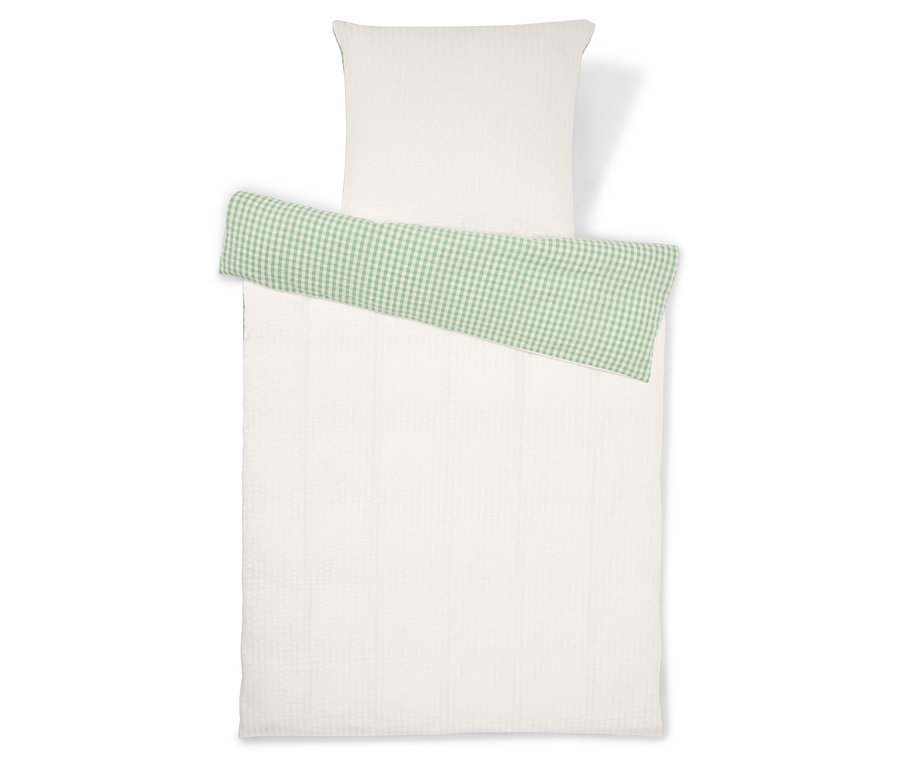 Ágyneműgarnitúra, amely egy fehér párnahuzatból és egy zöld kockás részlettel ellátott fehér paplanhuzatból áll.