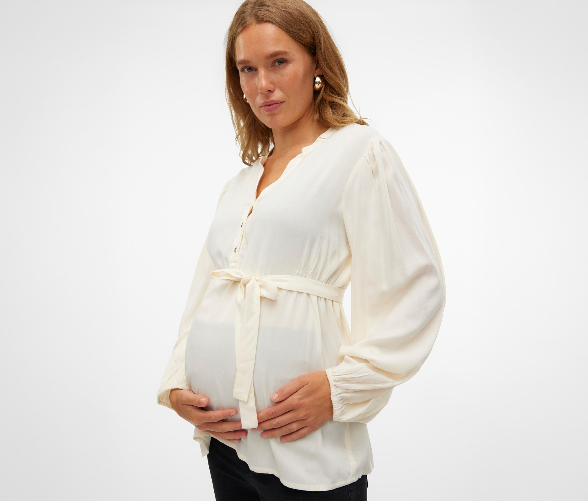Egy várandós nő fogja a hasát, és egy MAMALICIOUS MLMERCY LIA L/S WO kismamafelsőt visel.