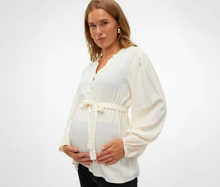 Egy várandós nő fogja a hasát, és egy MAMALICIOUS MLMERCY LIA L/S WO kismamafelsőt visel.