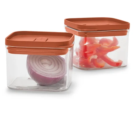 Két átlátszó, négyzet alakú tartály narancssárga fedővel. Az egyikben vöröshagyma, a másikban vágott piros paprika van.