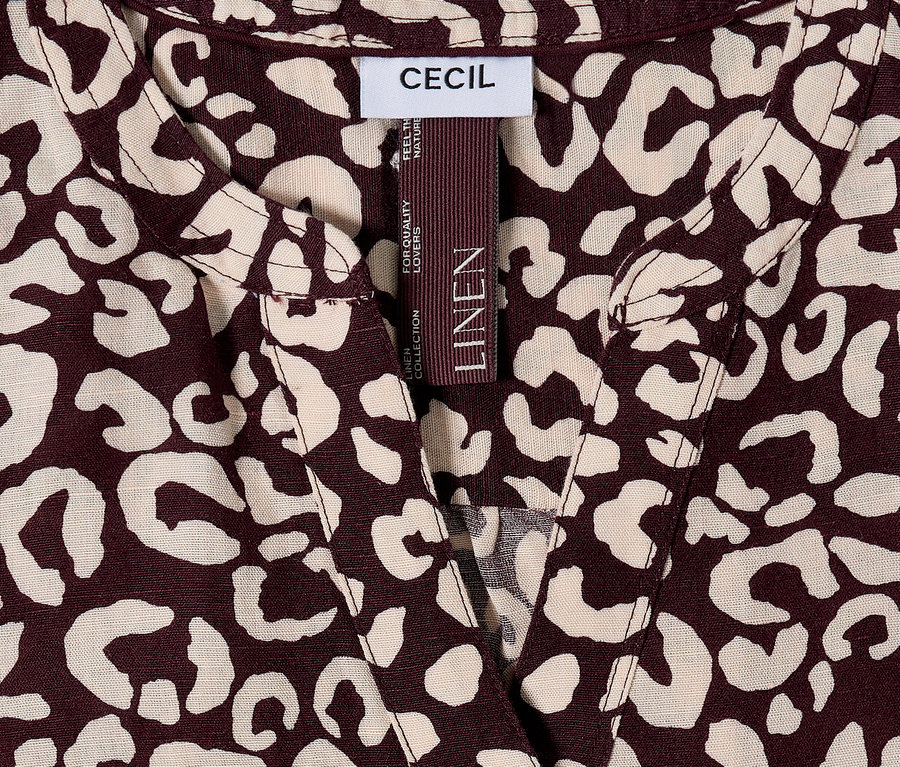 Közelkép egy barna és bézs leopárdmintás CECIL felsőről, LINEN címkével.