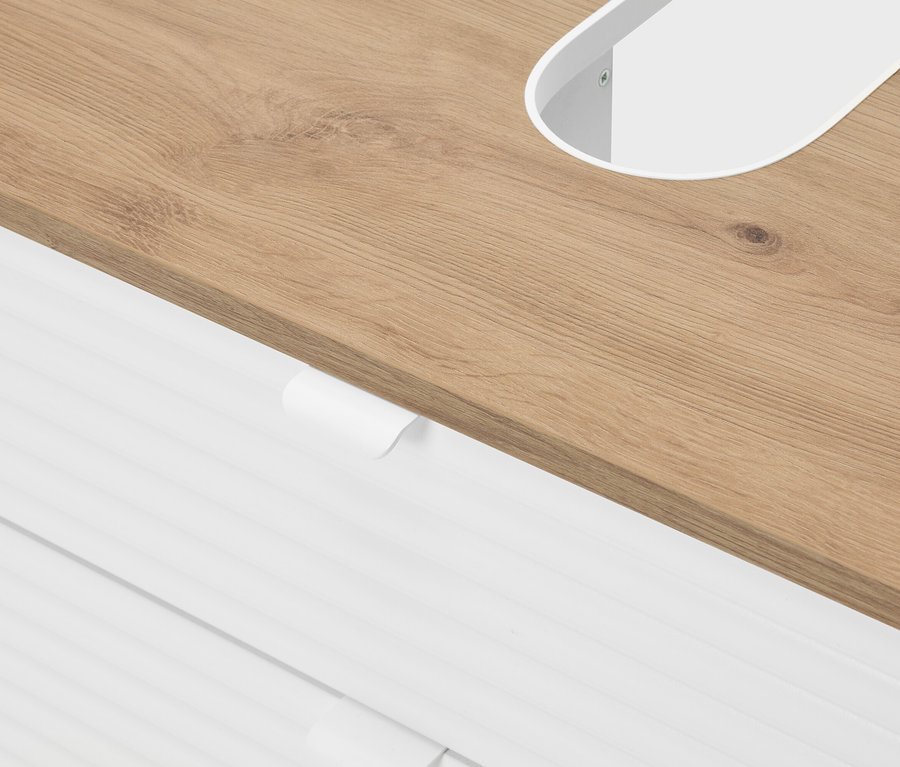 Egy világosbarna fa asztallap közeli képe, fehér, ovális kivágással és alatta fehér fiókokkal.