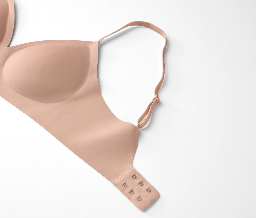 Egy testszínű melltartó fekszik egy fehér háttéren.