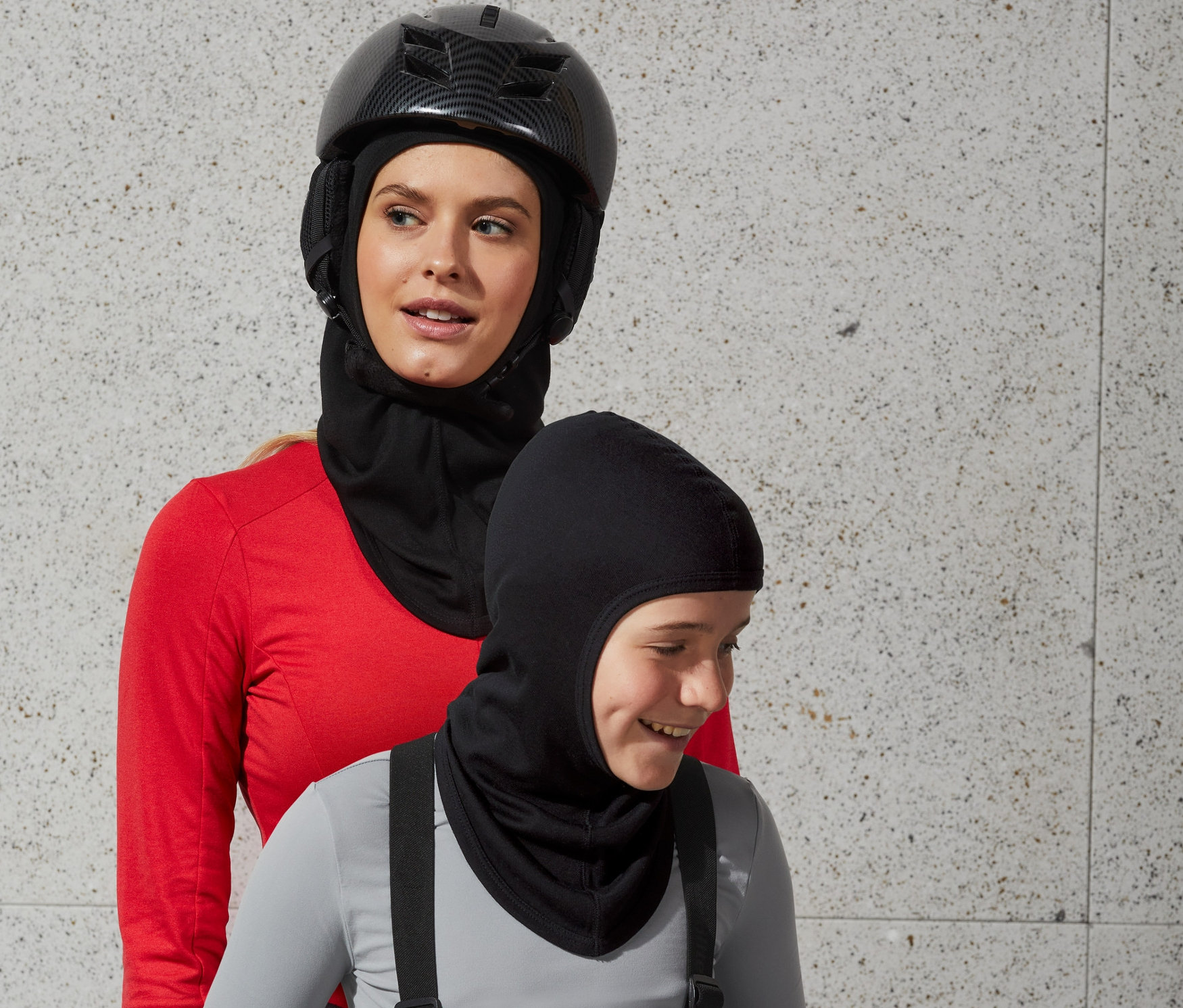 Sisakot és Performance kámzsát viselő nő áll egy kámzsát viselő fiú mögött.