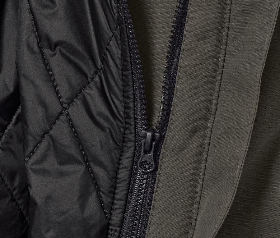 Egy 3 az 1-ben outdoor kabát részlete, mellény, cipzár és fekete, steppelt belső réteg.