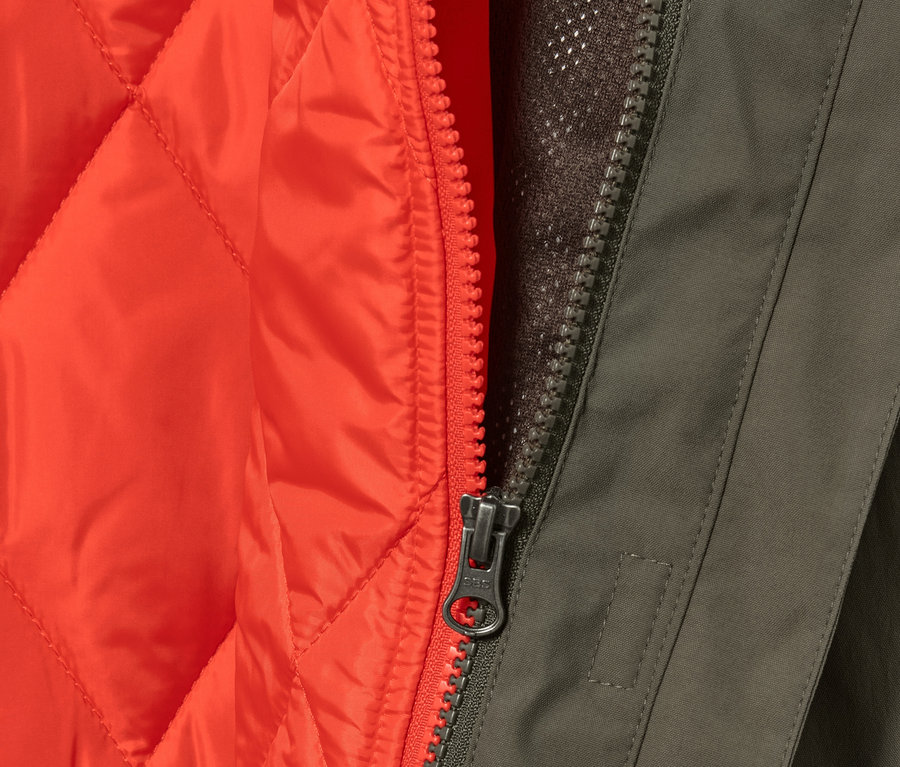 Egy olívazöld 3 az 1-ben esőkabát részlete narancssárga mellénnyel és cipzárral.