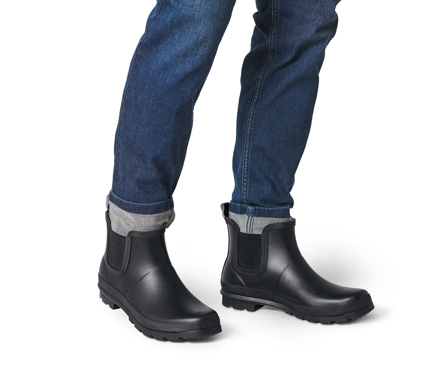 Farmerben és fekete férfi gumi bokacsizmában lábak.