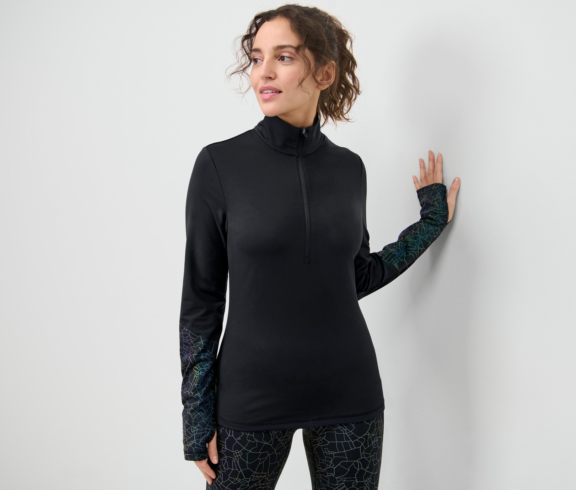 Nő pózol fekete, színes fényvisszaverő női funkcionális termofelsőben.
