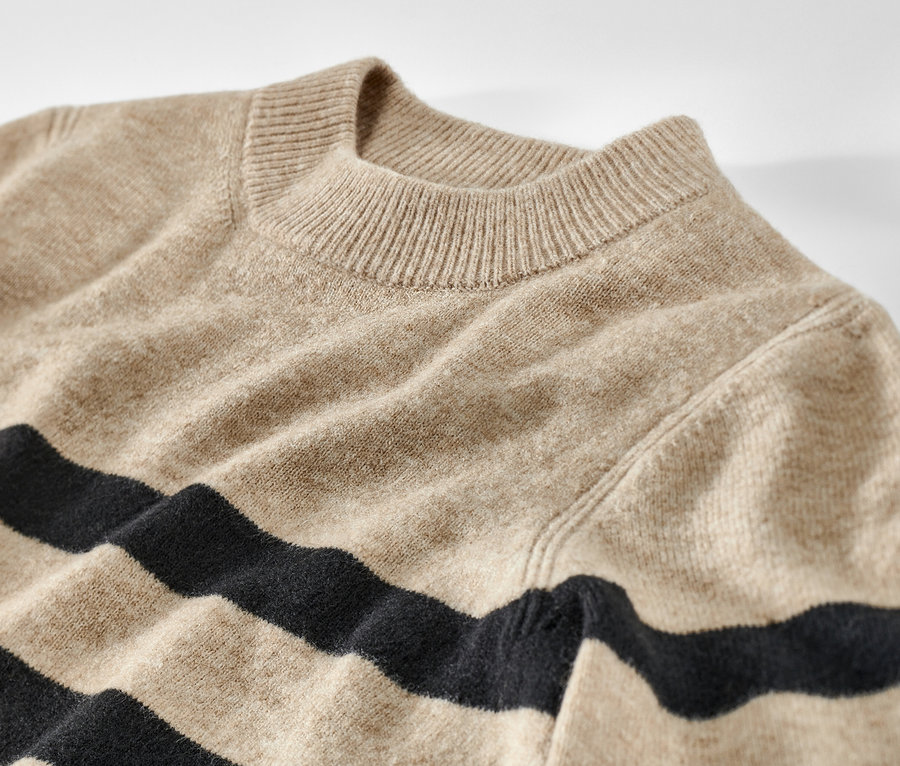 Egy csíkos kötött pulóver részletének képe.