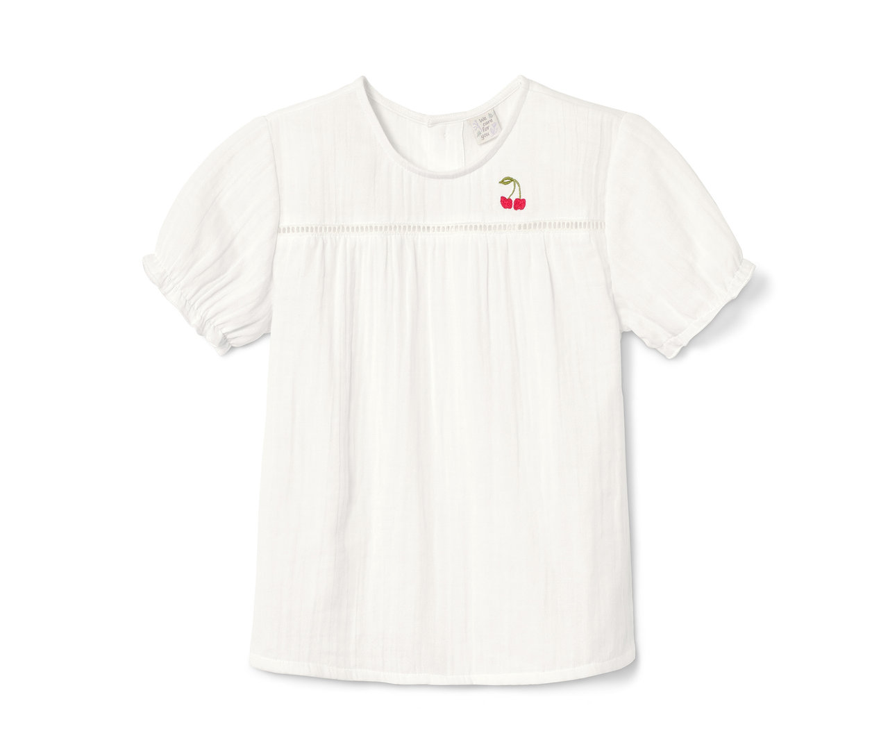 Egy fehér, rövid ujjú kislány blúz cseresznye hímzéssel.