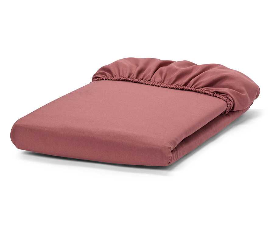 Összehajtott rózsaszín gumis lepedő.