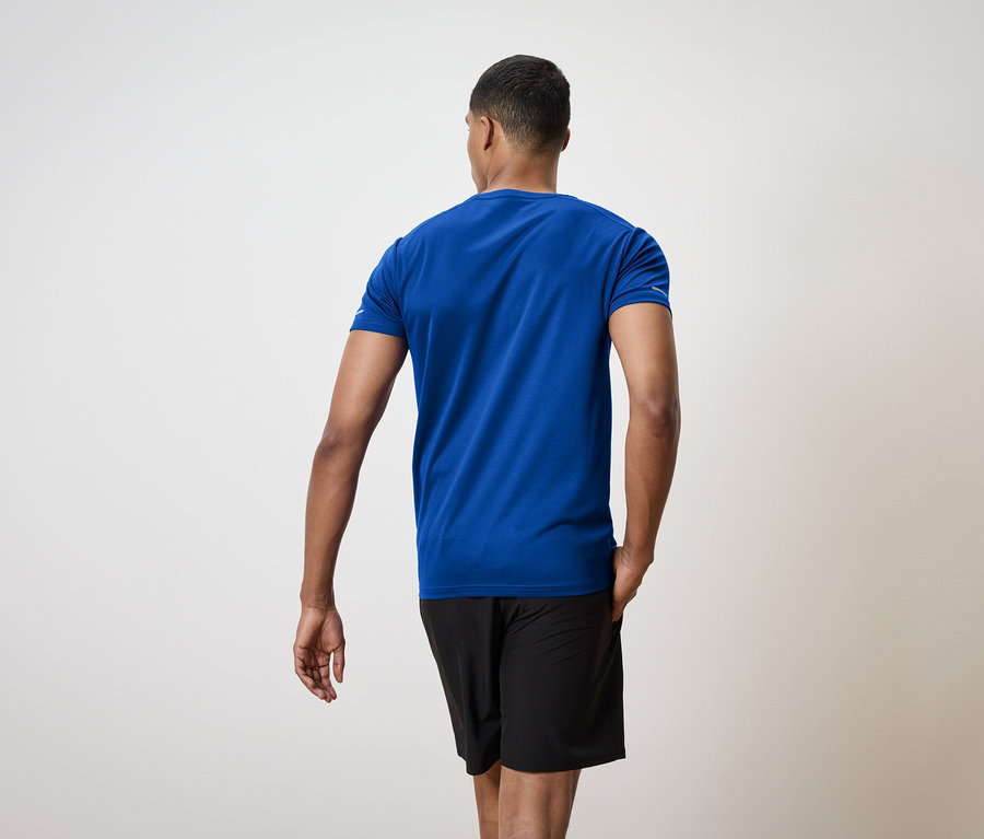 Egy férfi hátulról kék pólót és fekete rövidnadrágot visel.