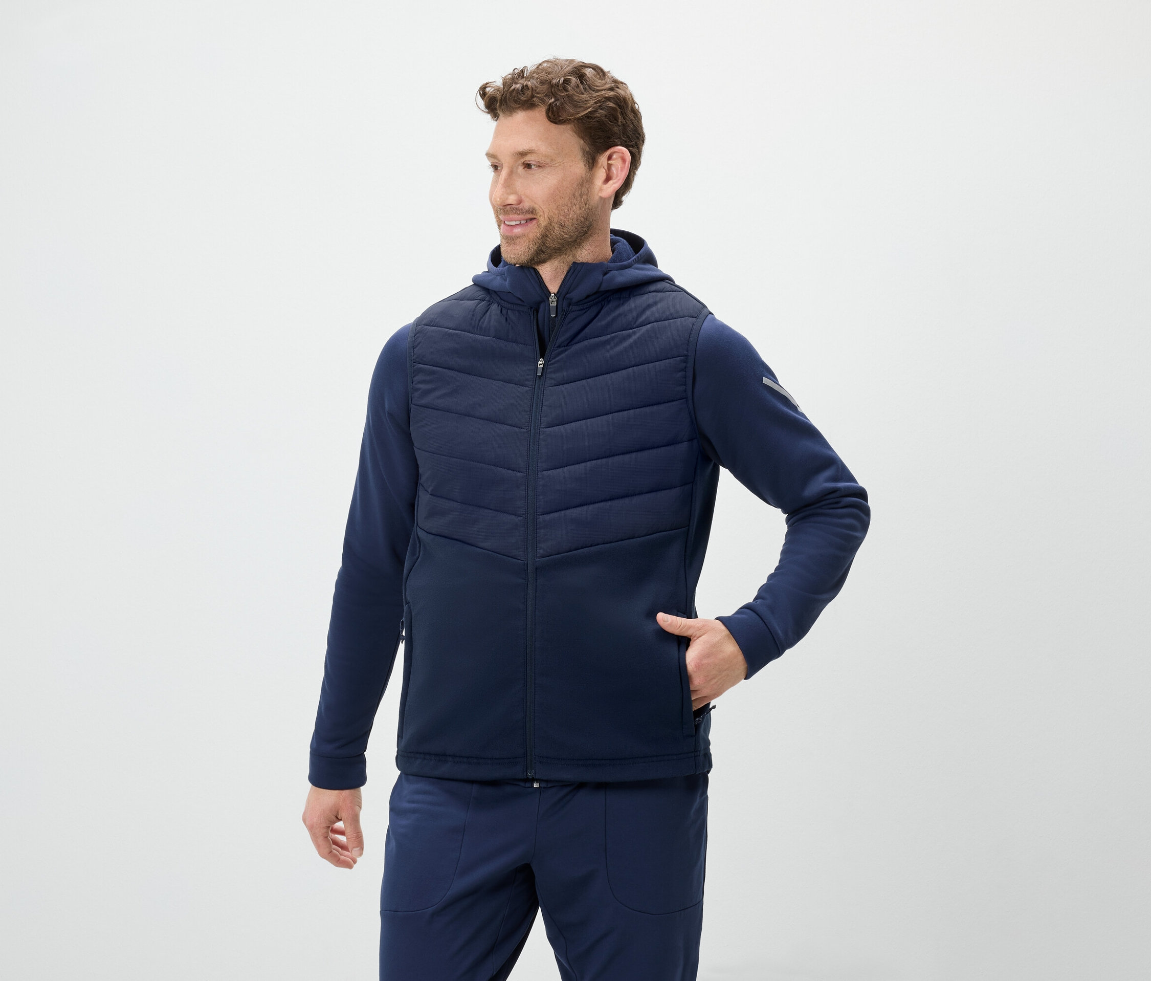Férfi kék kapucnis mellényt és kék melegítőalsót visel.
