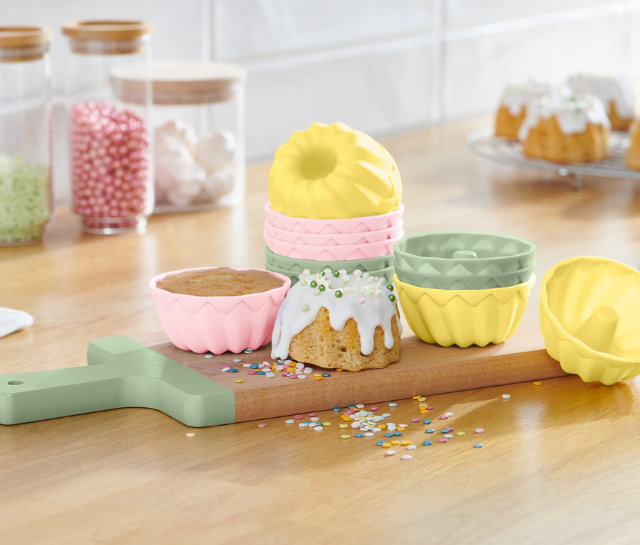 Gugelhupf formák egy fából készült deszkán kész gugelhupfokkal és szórással.