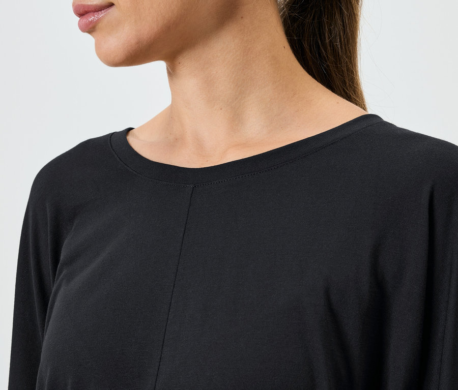 Egy női, fekete, hosszú ujjú felső részlete.