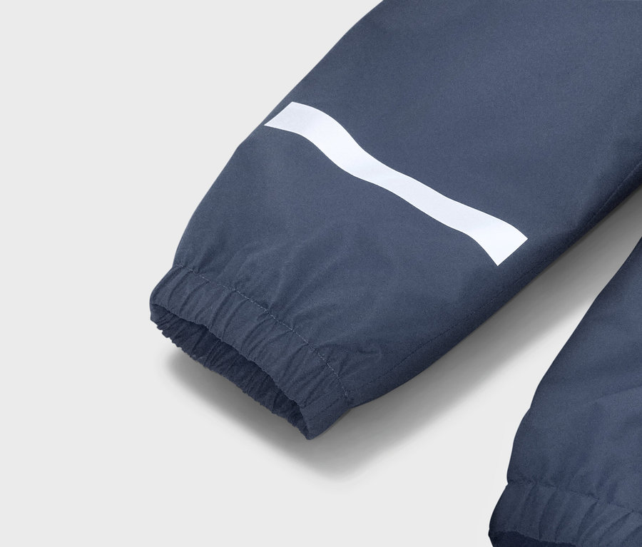 Egy kék kabátuj közelképe fehér, hullámos csíkkal és rugalmas mandzsettával.