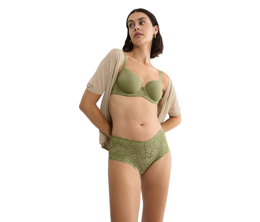 Nő visel zöld csipkés szegélyű melltartót és hozzáillő csipkés alsót, valamint egy bézs kardigánt.