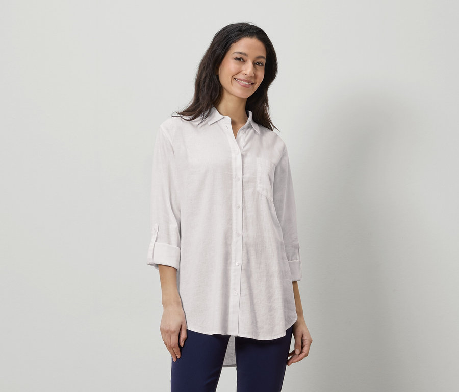 Nő visel egy fehér vászon inget és sötétkék nadrágot.