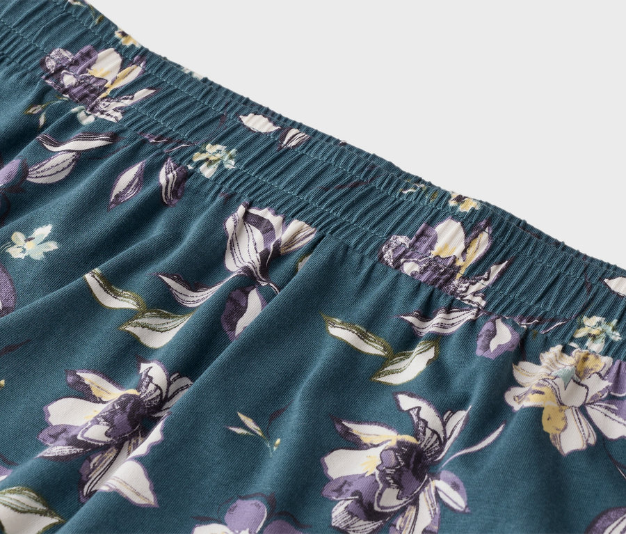 Kék pizsamanadrág közelképe, gumis derékpánttal és virágmintával.