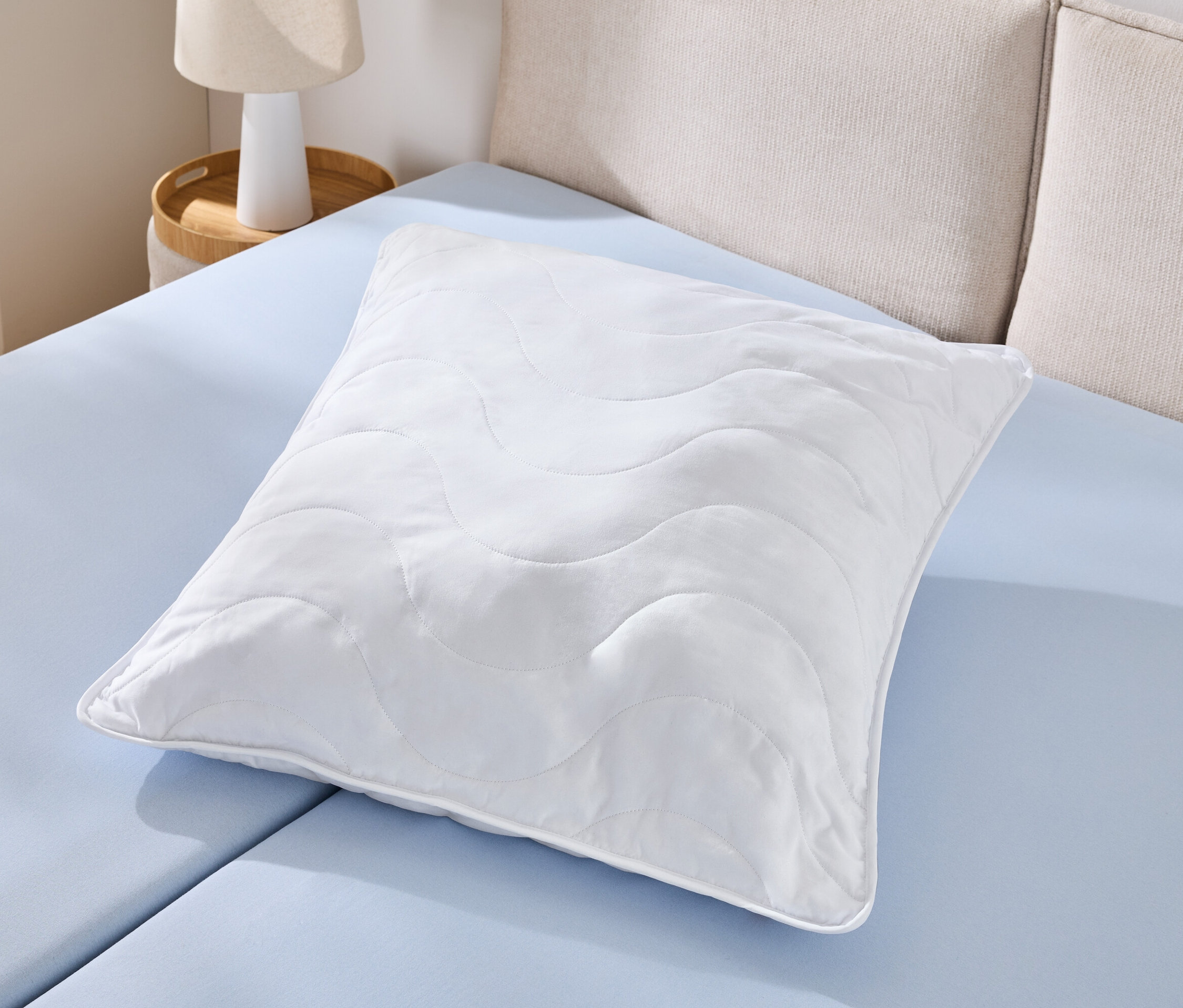 Egyetlen fehér, kifőzhető párna (kb. 90 x 70) fekszik egy világoskék lepedőn.
