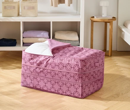 A fa padlón egy rózsaszín, geometrikus mintázatú tárolótáska áll, részben fehér takaróval megtöltve.